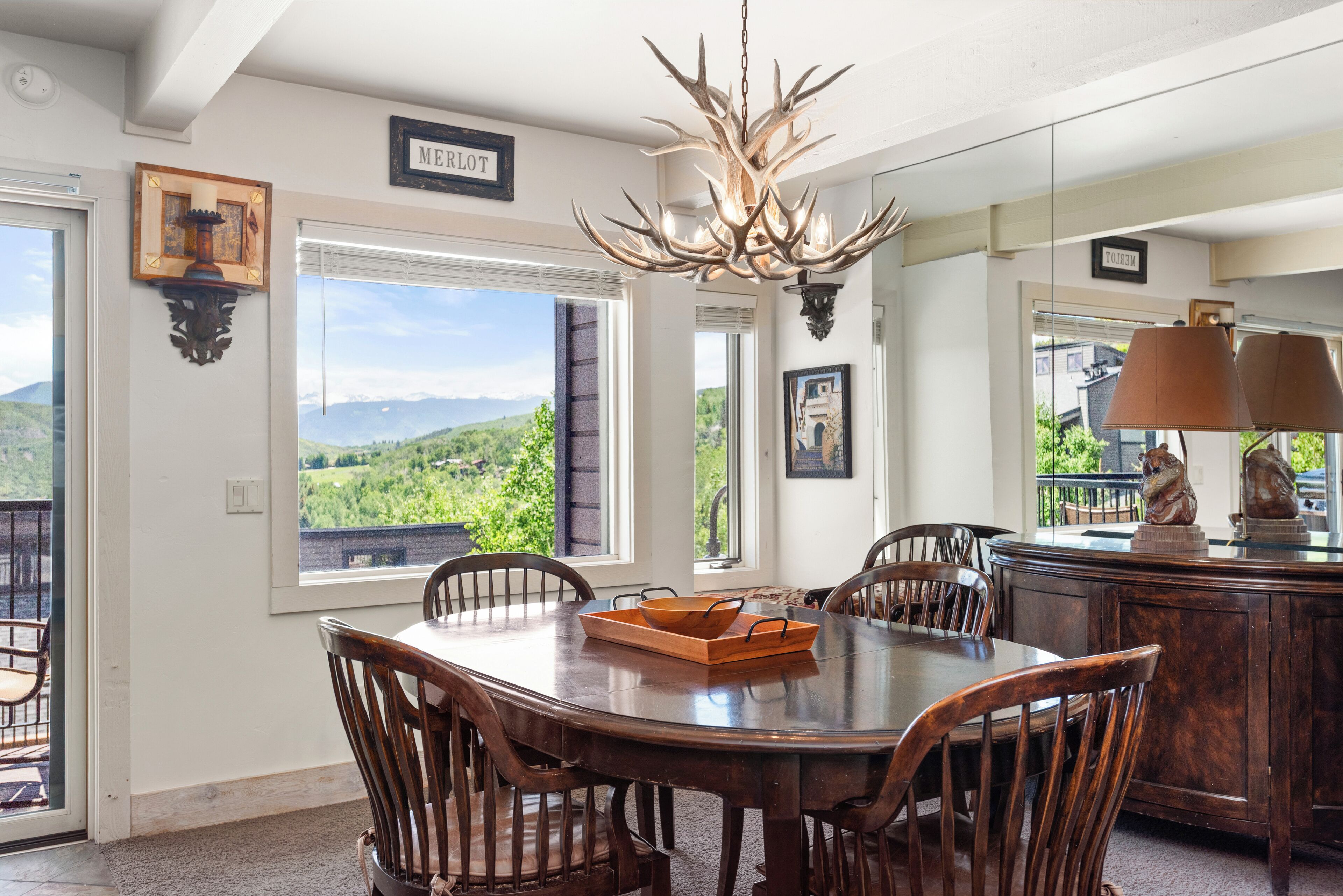 A dining area with a large wooden table, chairs, and a chandelier.