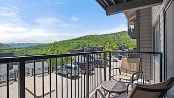 A balcony with a view of a parking lot and green hills.