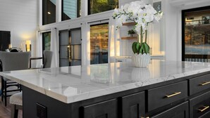 A modern kitchen with a large island, black cabinetry, and a white marble countertop. - Pool Table, Arcades, Great Views, Pets, Lazy Bear Retreat (Broken Bow)