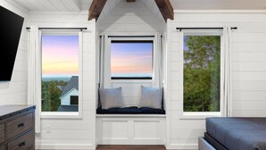Un dormitorio con una ventana con asiento integrado, una cama y un televisor montado en la pared.