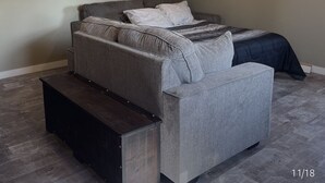 A bedroom with a bed, a sofa, and a bench. - WATER FRONT & BACK 4 SEASON GETAWAY AT THE BAY.
Relax with family & friends. (Blenheim)