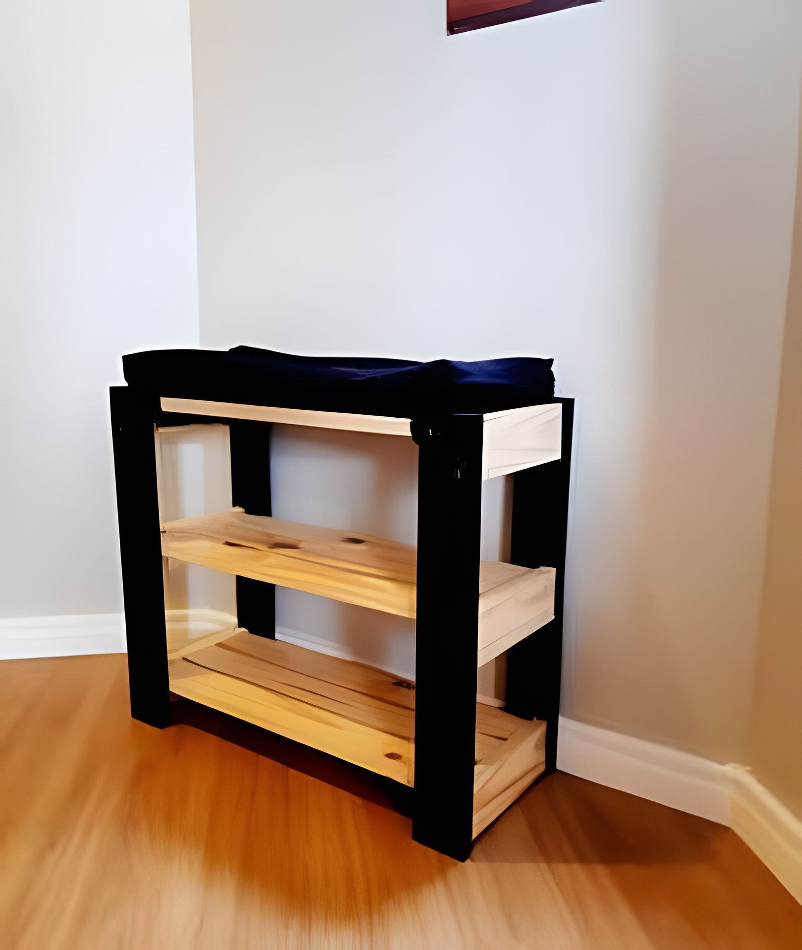 A black and white shelf unit with three shelves against a white wall.
