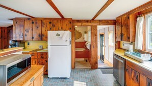 Una cocina compacta con armarios de madera, un refrigerador blanco, un microondas y un lavamanos.
