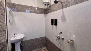 A modern bathroom with a sink, mirror, shower, and towel racks. - Prithvi Hotel (Rishikesh)
