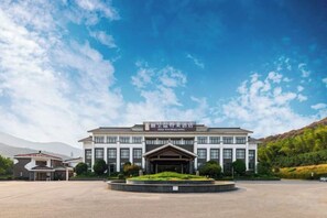 A large building with a central entrance, surrounded by a landscaped area. - Winterless Hotel Wuxi (Wuxi)