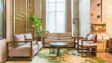 En moderne hotellobby med sofasæt, rundt sofabord og en dekorativ plante.