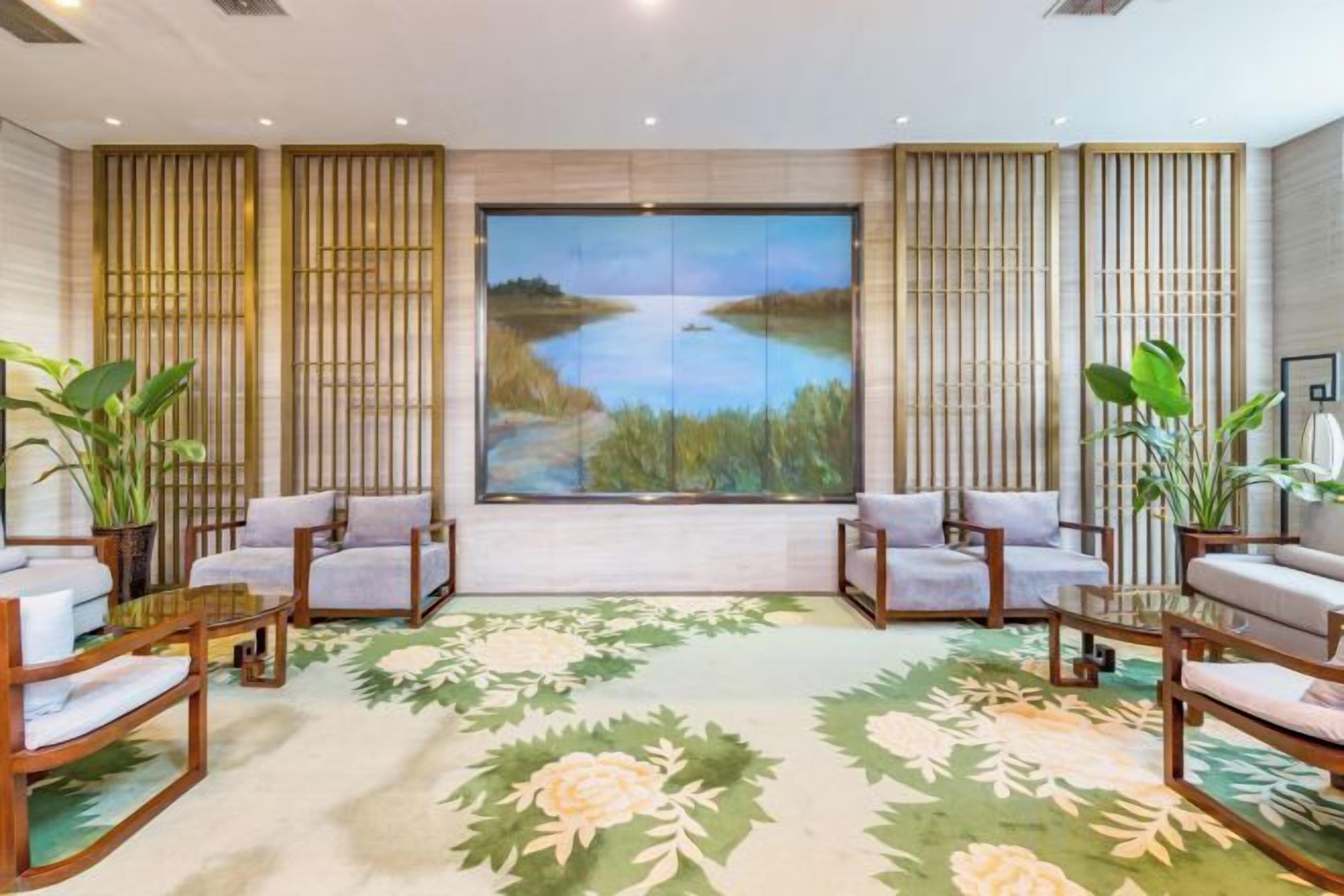 A room with a large window, two sofas, a coffee table, and a floral carpet.