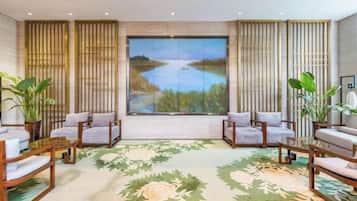 A room with a large window, two sofas, a coffee table, and a floral carpet.