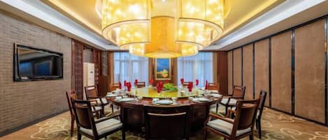 Une salle de conférence avec une table ronde, des chaises et un grand lustre.