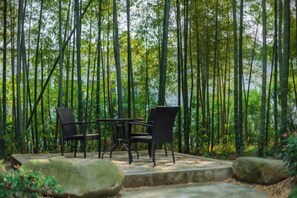 An outdoor seating area with a table and chairs, surrounded by a forested environment. - Winterless Hotel Wuxi (Wuxi)