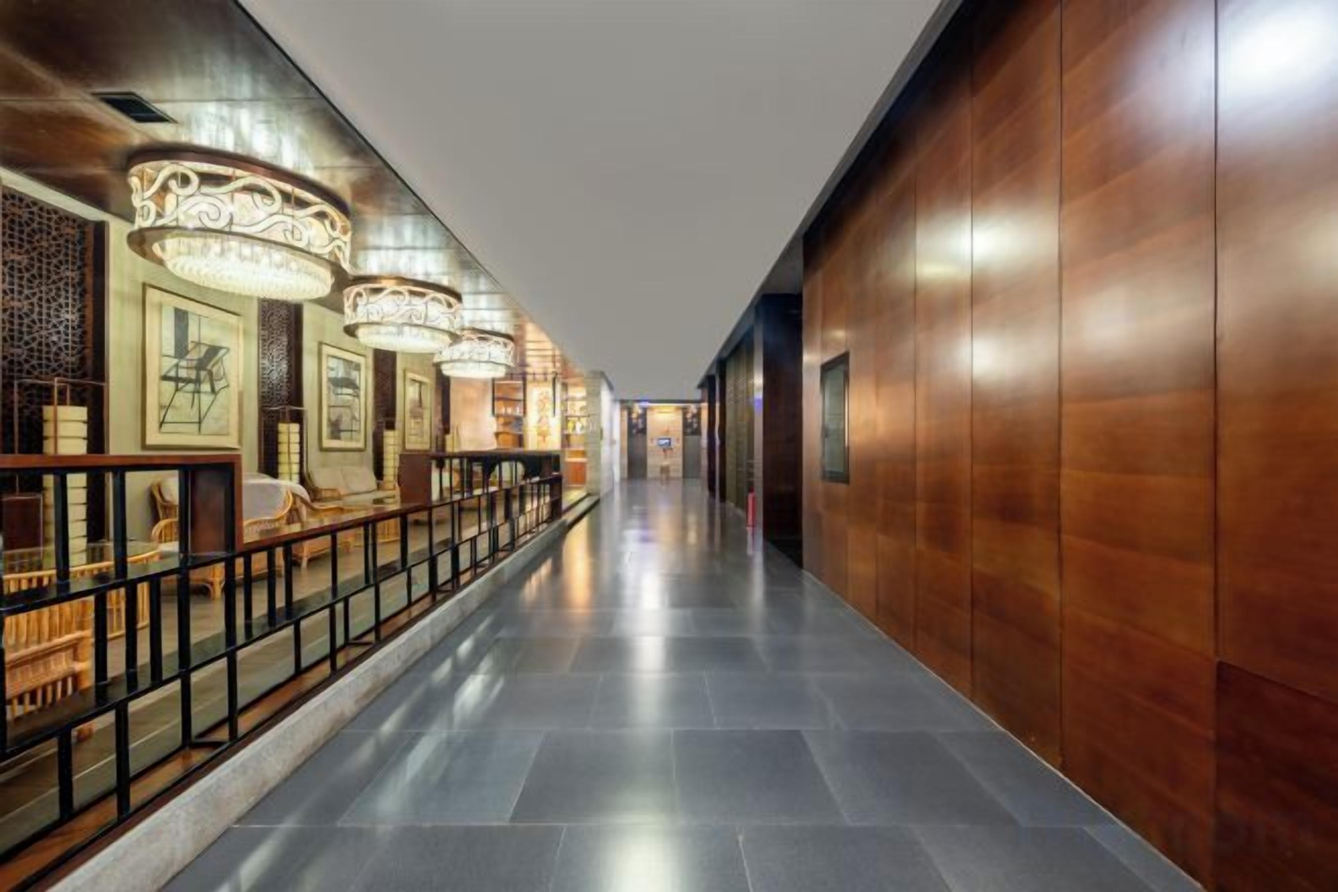 A corridor with a wooden wall, a railing, and hanging lamps.