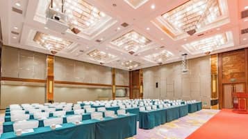 A conference room with rows of tables, a stage, and a red carpet.