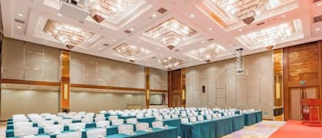 A conference room with rows of tables, a stage, and a red carpet.