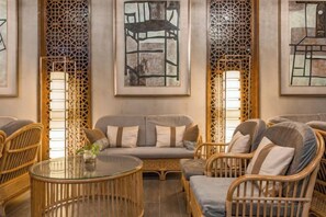 A room with wicker furniture, a glass coffee table, and artwork on the walls. - Winterless Hotel Wuxi (Wuxi)