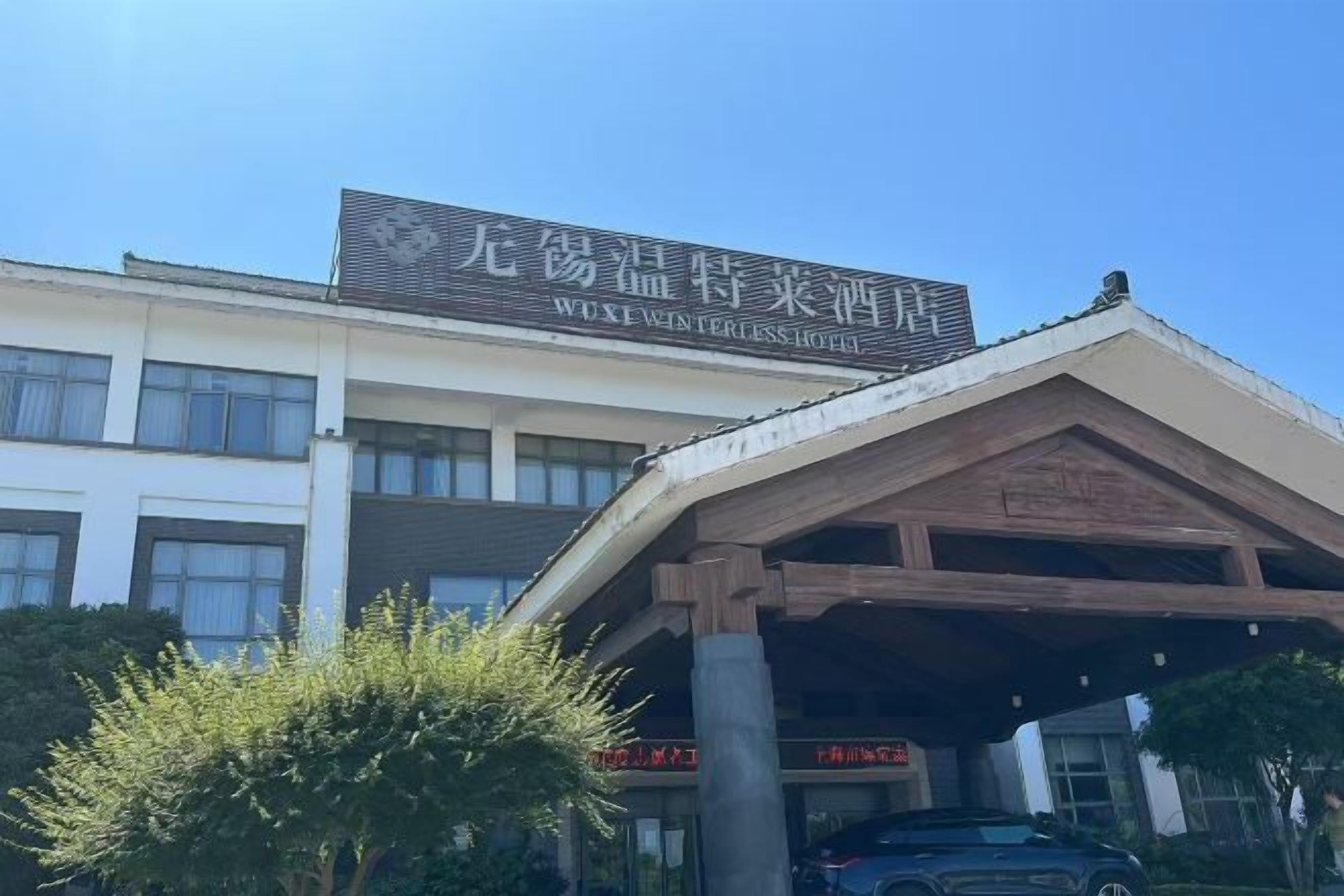 Ein Hotel mit auffälliger Schrifttafel, überdachter Eingangspartei und blauem Himmel.