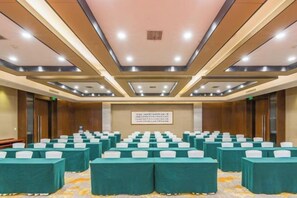 Un salón de conferencias con filas de mesas y sillas, una pantalla grande y un revestimiento de pared de madera.