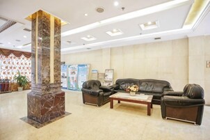 Un vestíbulo con una columna de mármol, sofás de cuero, una mesa de centro y un mostrador de recepción.