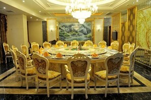 A round dining table with chairs, a chandelier, and a large painting on the wall.