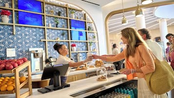 Un café moderno con mostrador, una variedad de pasteles y una exhibición de bebidas embotelladas.