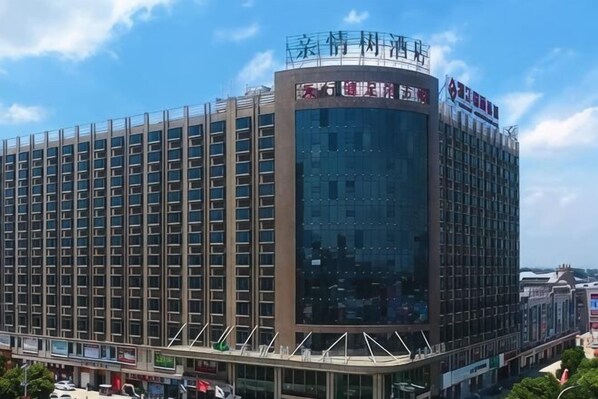 A multi-story hotel with a modern design, featuring a prominent glass facade and a flat roof. - Qinqingshu Hotel (Zhumadian)