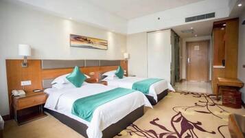 A hotel room with two beds, a nightstand, a desk, and a chair.