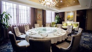 A dining area with a round table, chairs, and a chandelier.