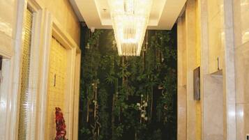 Un pasillo con una araña, una estatua decorativa y un muro con vegetación vertical.