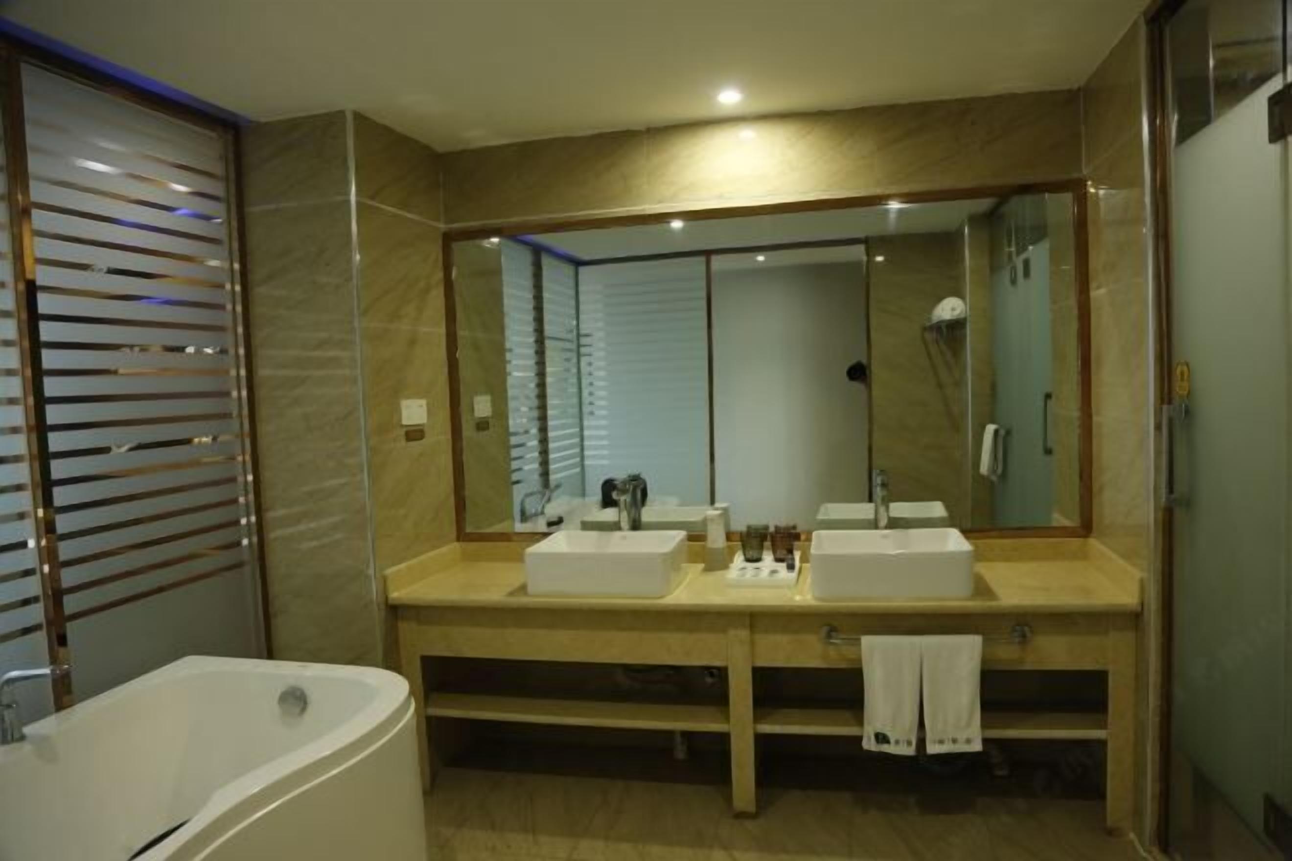 Un baño moderno con un espejo grande, dos lavamanos, una bañera y una ducha.