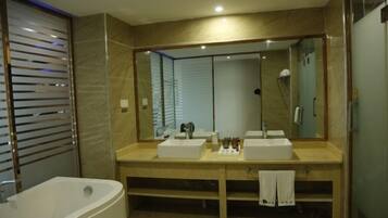 Un baño moderno con un espejo grande, dos lavamanos, una bañera y una ducha.