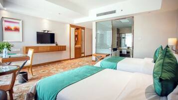 Habitación de hotel con dos camas, un escritorio con una silla, televisor y un espejo grande.