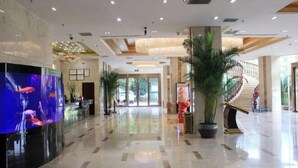 A spacious lobby with a large aquarium display, a staircase, and potted plants.