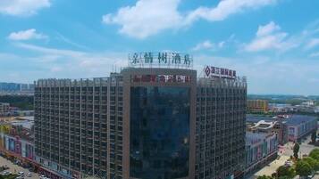 A multi-story hotel with a modern architectural design, featuring a prominent glass facade and a rooftop terrace.