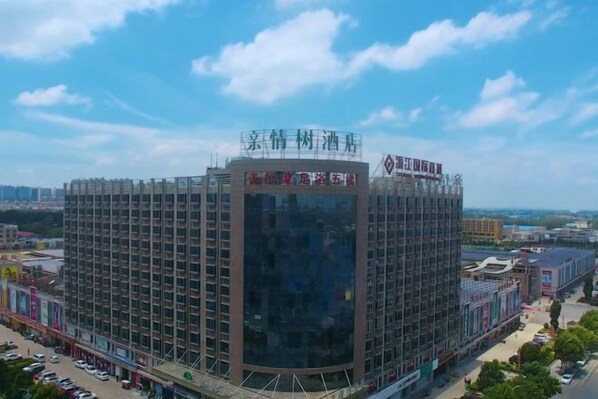 A multi-story hotel with a modern architectural design, featuring a prominent glass facade and a rooftop terrace.