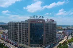 Un hotel de varios pisos con un diseño arquitectónico moderno, que destaca por su fachada de vidrio y una terraza en la azotea.