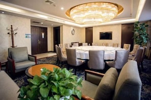 A conference room with a round table, chairs, a chandelier, and a potted plant. - Qinqingshu Hotel (Zhumadian)