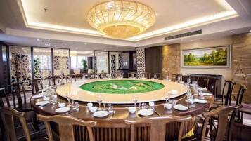 Una mesa redonda de comedor con sillas, una araña y un centro decorativo.