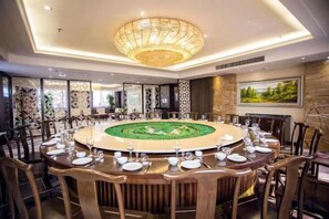Una mesa redonda de comedor con sillas, una araña y un centro decorativo.