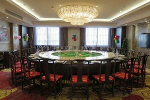 Une salle de conférence avec une table ronde, des chaises et un lustre.