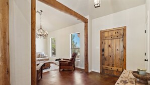 A spacious room with a wooden door, a chandelier, a sofa, and a table. - Hot Tub-Pool-Amazing Views! Sleeps 18! (Tucson)