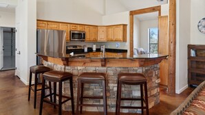 A kitchen with a stone island, wooden cabinets, stainless steel appliances, and bar stools. - Hot Tub-Pool-Amazing Views! Sleeps 18! (Tucson)