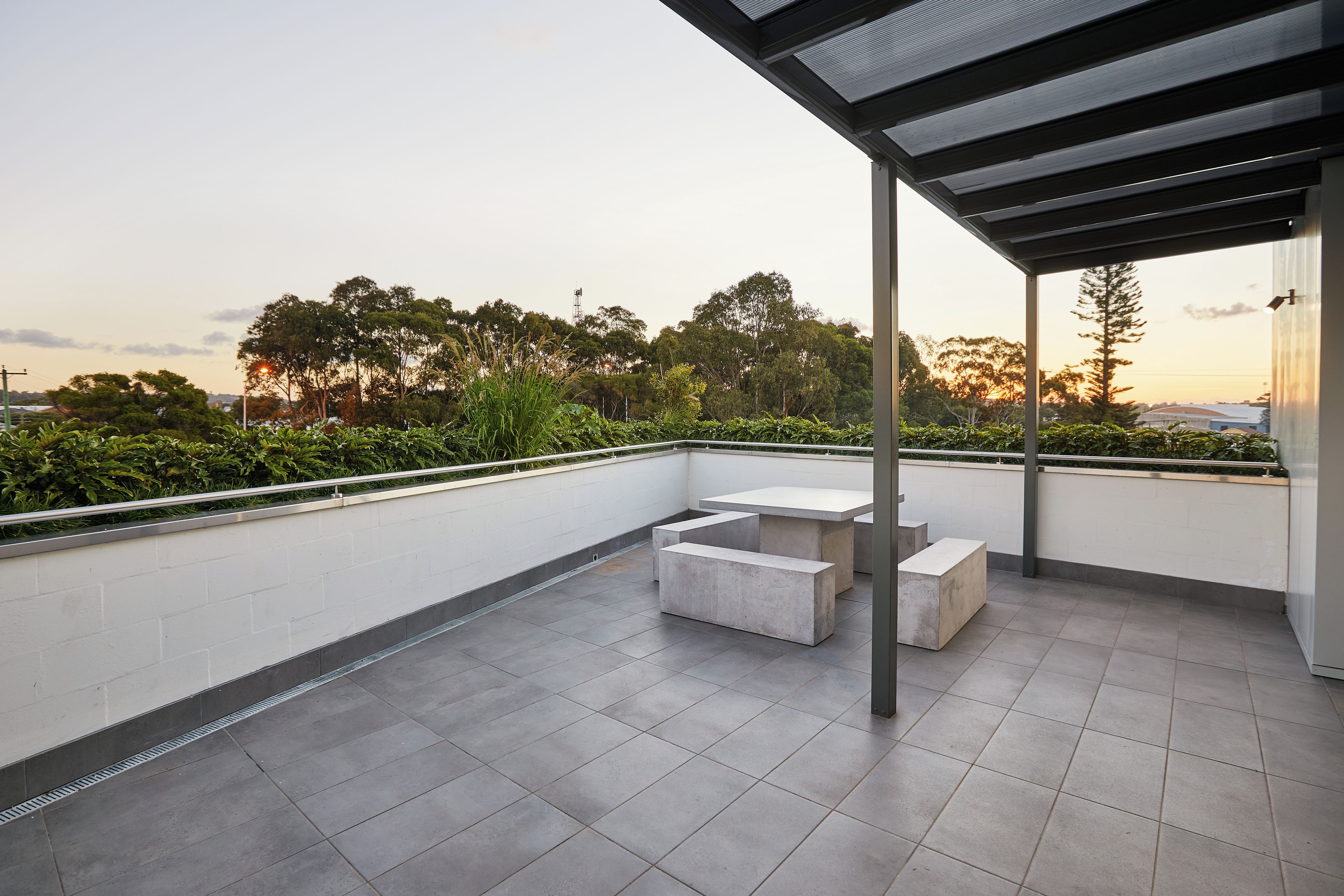 A rooftop terrace with a pergola, a table, and benches.