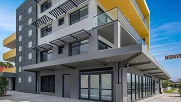 A modern multi-story building with a flat facade, large windows, and a yellow accent wall.