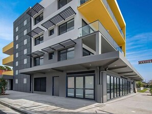 A modern multi-story building with a flat facade, large windows, and a yellow accent wall.