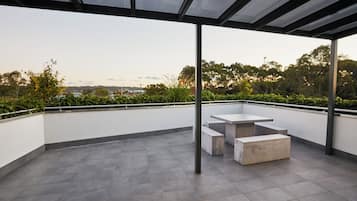 A rooftop terrace with a modern design, featuring a glass ceiling and a minimalist seating area.