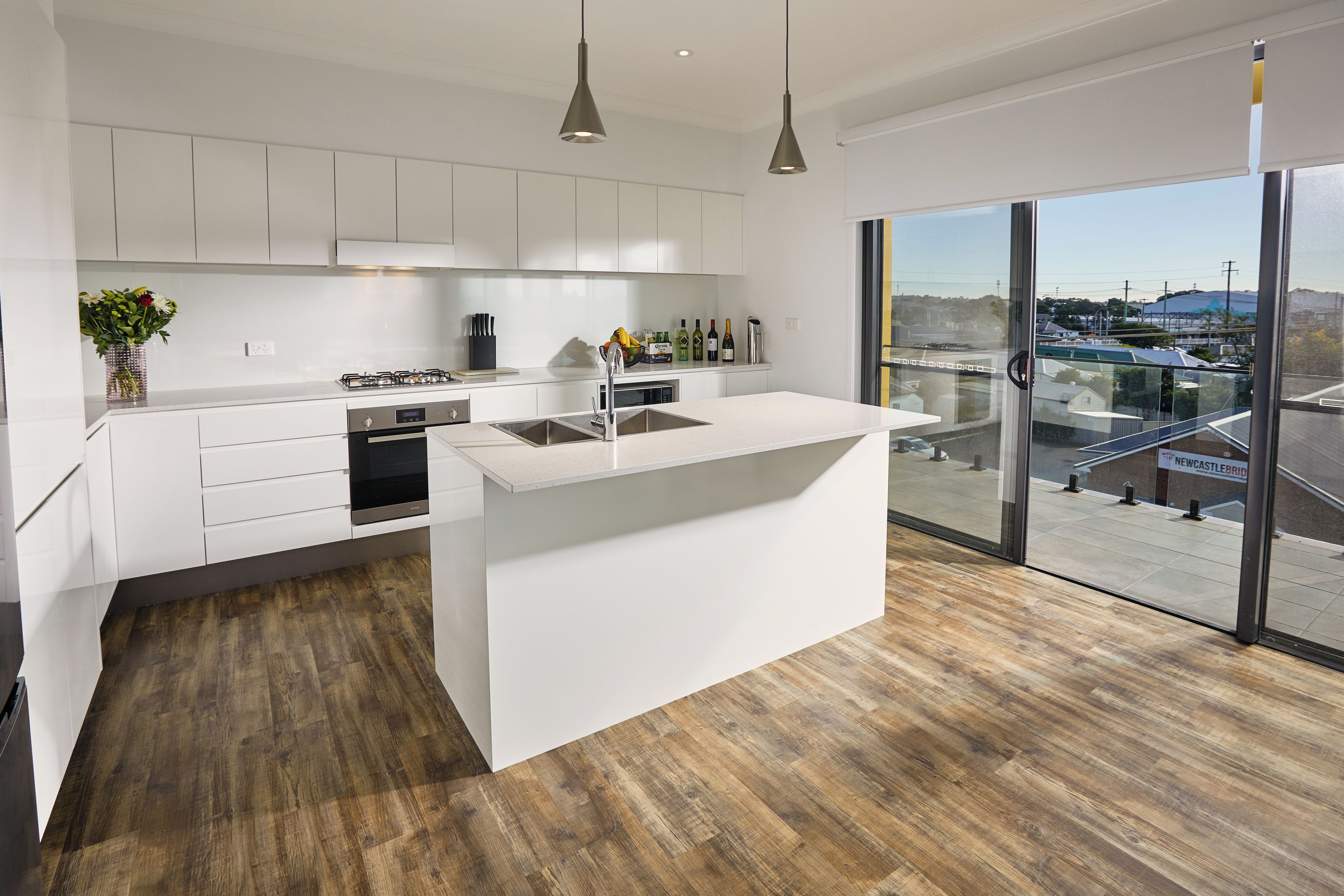 A modern kitchen with white cabinetry, a central island, and a large window offering a view of the outside.