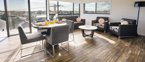 Ein modernes Wohnzimmer mit Essbereich, großen Fenstern und Blick auf die Stadt.