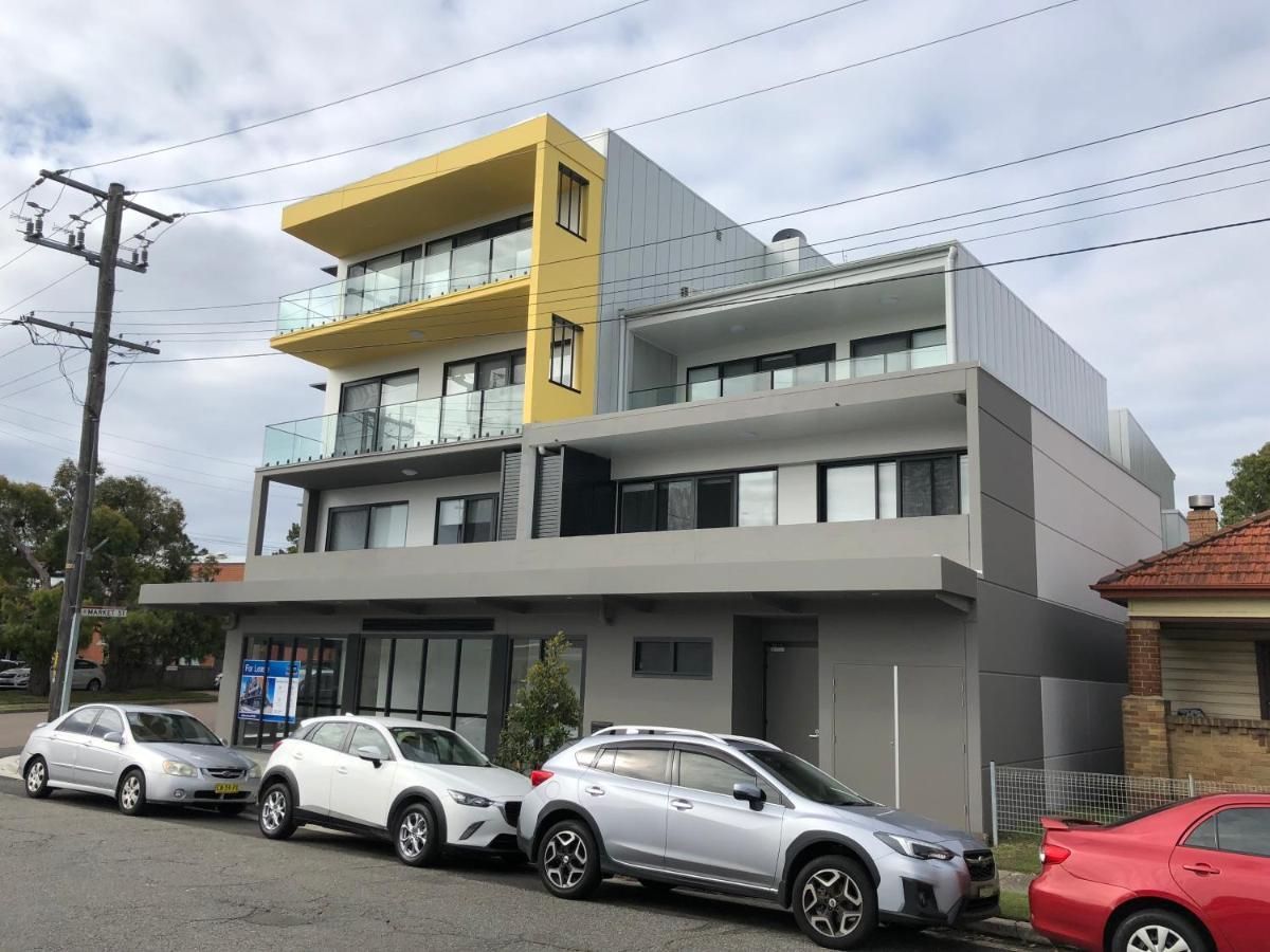 A modern two-story building with a flat roof and a yellow accent on the upper level.