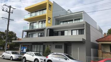 A modern two-story building with a flat roof and a yellow accent on the upper level.