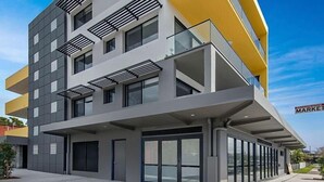 A modern multi-story building with a flat facade, large windows, and a yellow accent wall. - Nouveau Serviced Apartments (Newcastle)