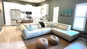 Una sala de estar moderna con un sofá seccional, un comedor y una cocina.